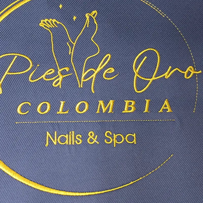 Logotipo bordado en hilo dorado sobre tela azul marino